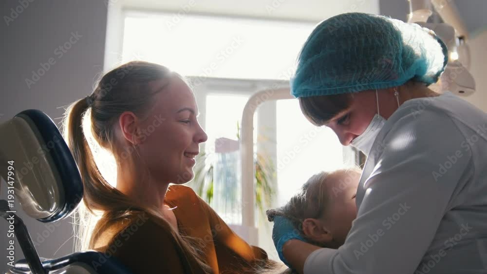 Little child with mommy in stomatology chair - girl is smiling Little child with mommy in stomatology chair - girl is smiling