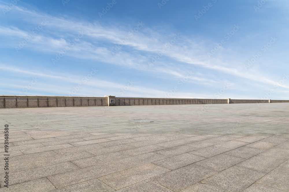 Asphalt pavements and square floor tiles under the blue sky and white clouds