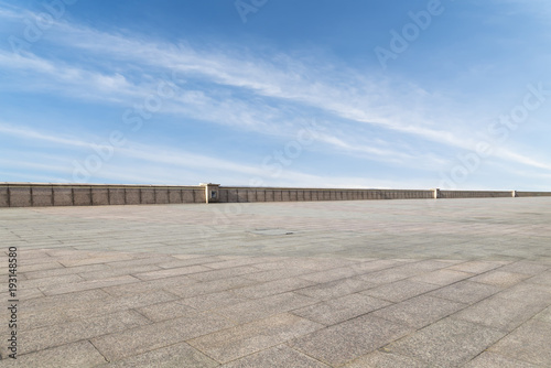 Asphalt pavements and square floor tiles under the blue sky and white clouds