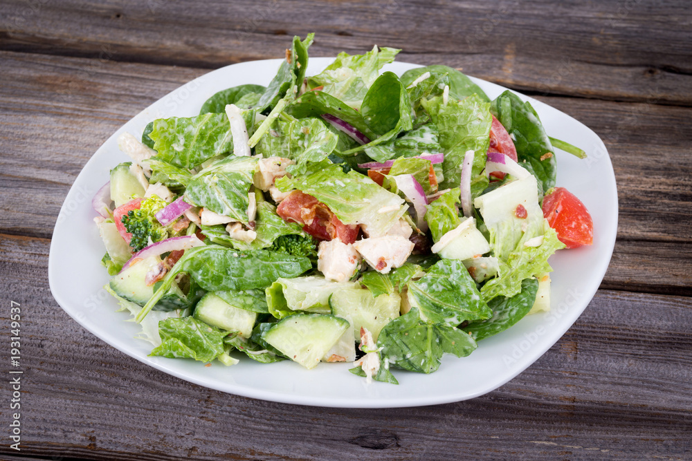Chicken and vegetable salad with ranch dressing over wooden background table Chicken and vegetable salad with ranch dressing over wooden background table