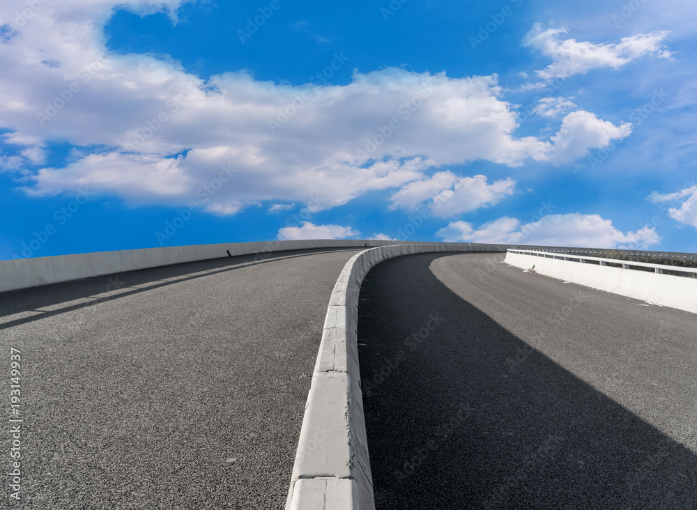 Fototapeta premium Asphalt pavements and square floor tiles under the blue sky and white clouds