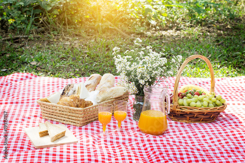 Picnic Lunch Meal Outdoors Park Food Concept, Closeup of picnic basket with drinks, food and flowers on the grass.