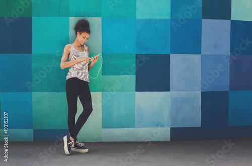 African-american woman posing, leaning on bright wall photo