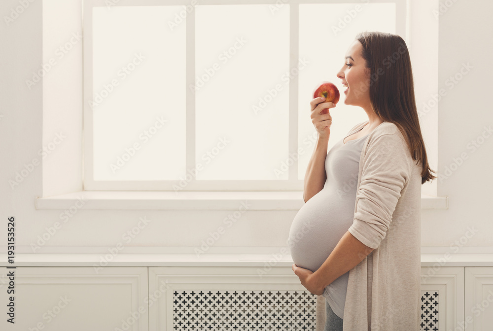 Pregnant woman eating apple at home copy space Pregnant woman eating apple at home copy space