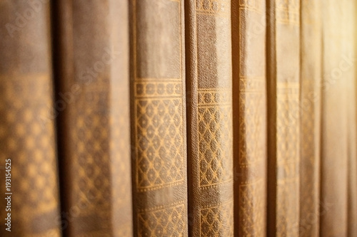 Closeup view of row of books with leather vintage cover standing on bookshelf. Perspective view