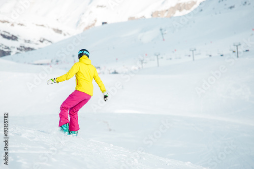 Image from back of girl in sports clothes snowboarding