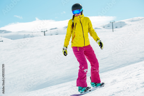Picture of young athlete girl wearing helmet in sports clothes snowboarding
