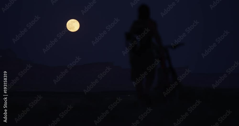 Person walks bike under full moon, wide Person walks bike under full moon, wide