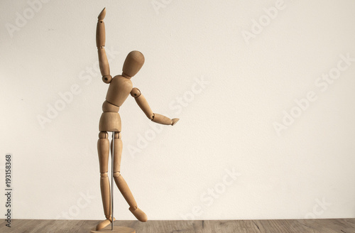 Wooden dummy toy poses on white wall background photo