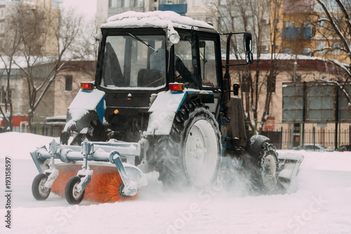 A tractor with brushes removes snow on the rink