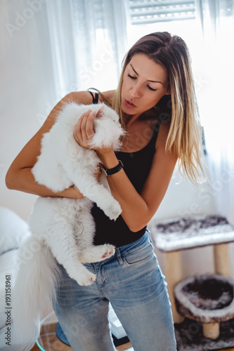 Girl trying to kiss a cat in her home photo