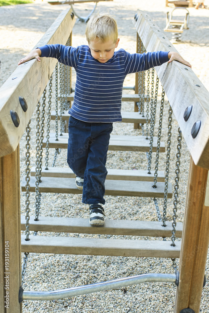 The boy is on the rope bridge in the Playground. The child