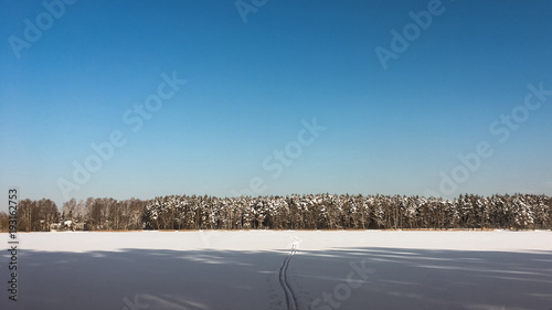 Sun  snow and Ski track crossing a frozen lake. Winter sport - cross-country skiing.