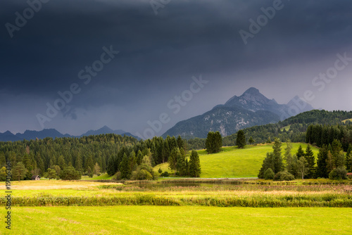 Alpine valley against mountain under dramatic thundercloud, raining © Yury Kirillov