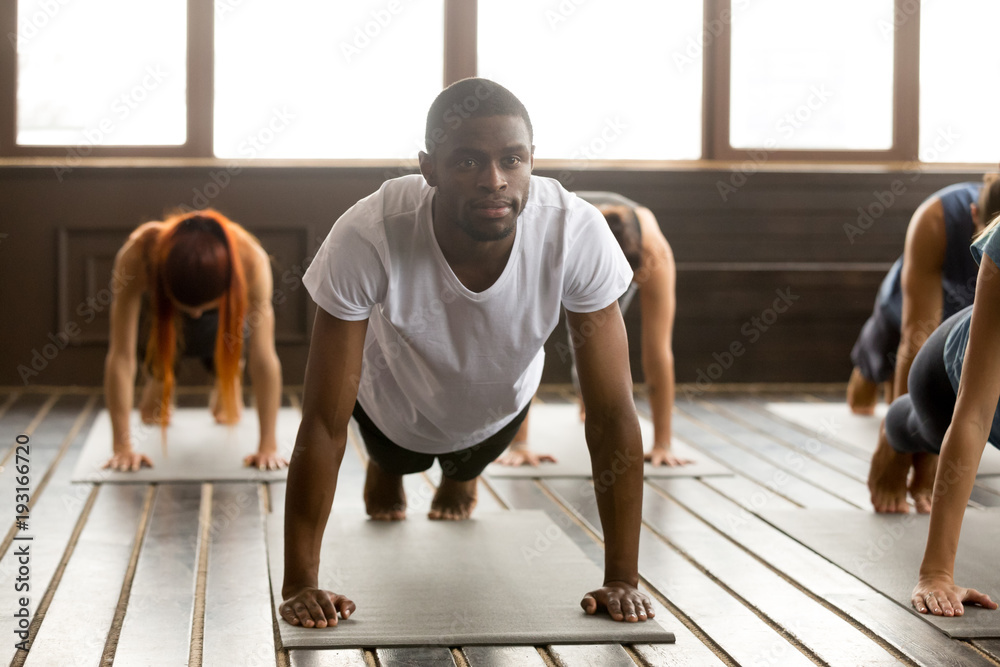 Portrait of young happy black man and a group of sporty people practicing  yoga lesson standing