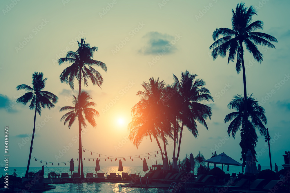 Fototapeta premium Silhouettes of palm trees on a tropical sea beach during amazing sunset.