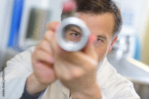 View of male scientist through metal tube