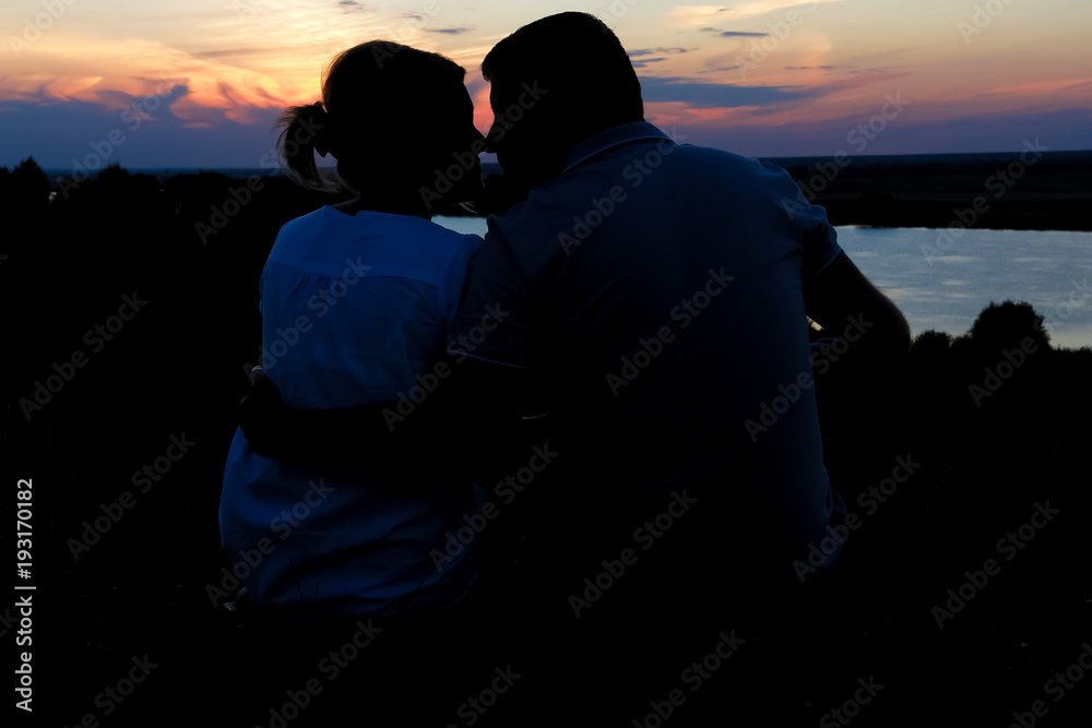 Young couple silhouette against sunset sky. Romantic evening.