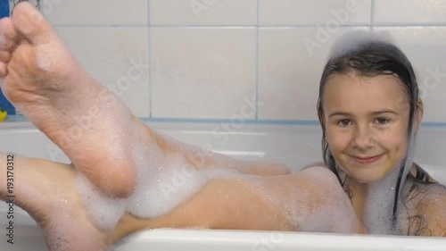 Little girl takes a bath. Funny little girl in foam in the bathroom.