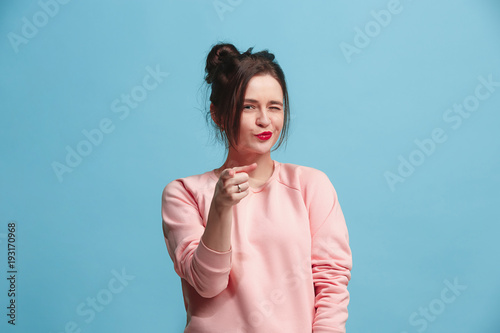 The happy business woman point you and want you, half length closeup portrait on blue background.