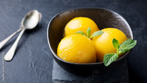 Canvastavla Mango ice cream, tropical fruit sorbet in black bowl on stone background