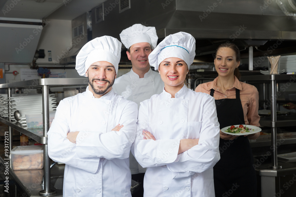 Two chefs in kitchen with staff