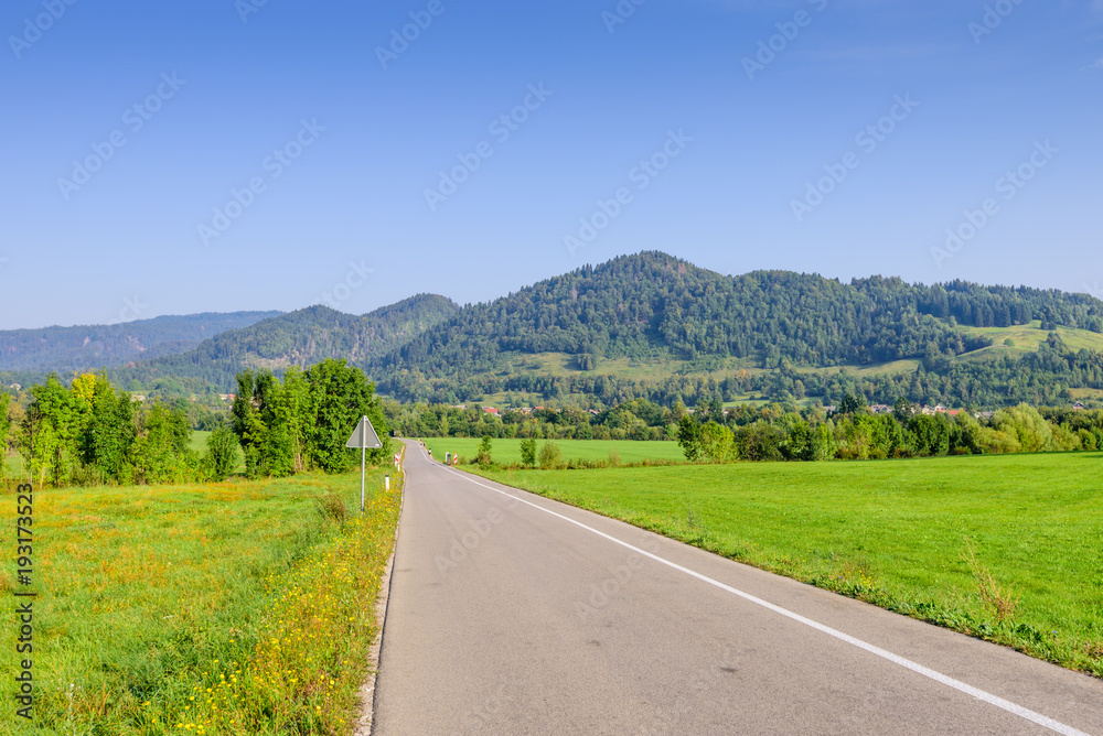 Pictorial field and an asphalt road on the background of mountain peaks, Bled, Slovenia.