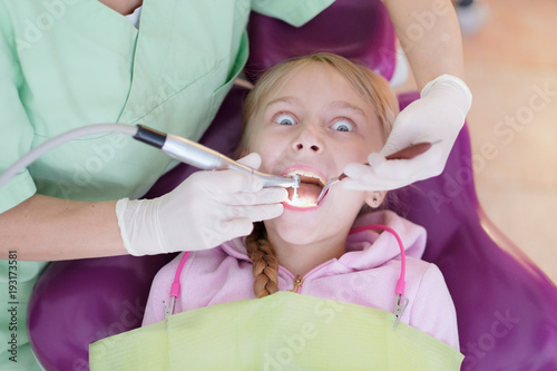 A little girl is lying in an armchair at a reception near a dentist