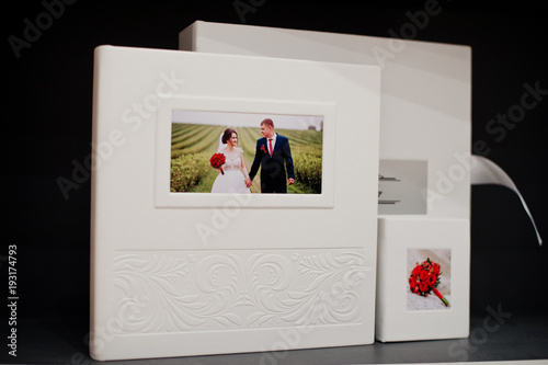 Elegant white or beige photobook, photoalbum and a flash drive case on black background.