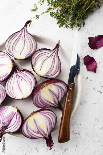 Red sweet onions halves on a white plate on a light background. Top View. photo