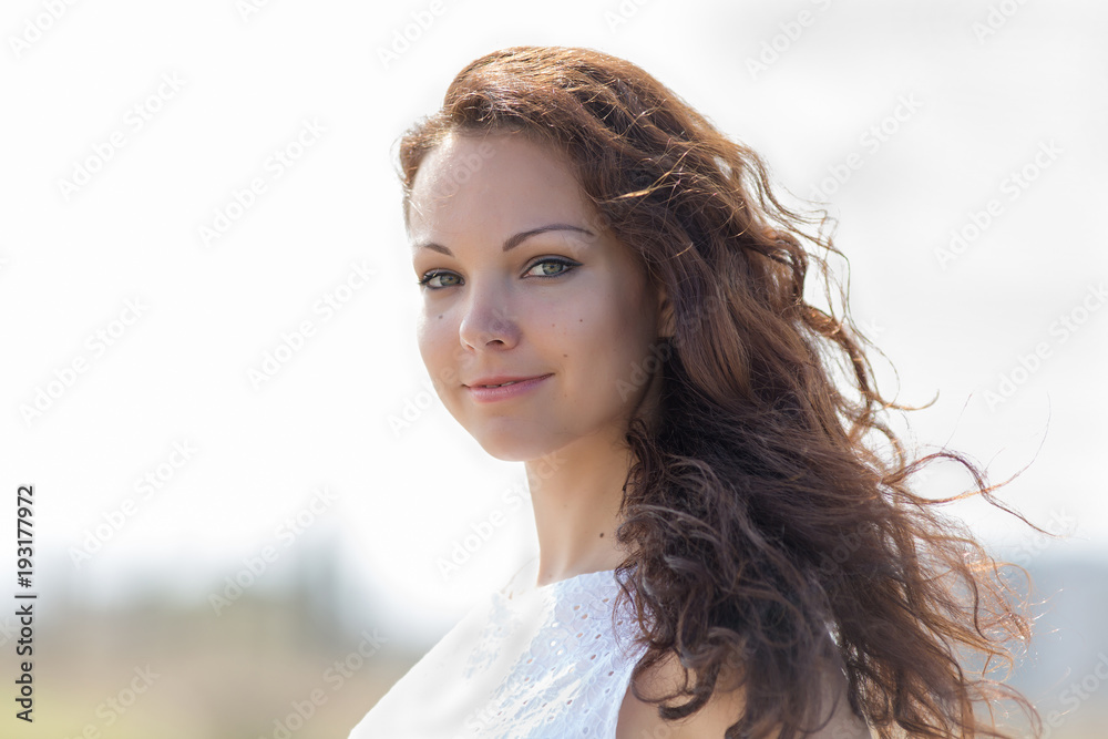 Woman in white sleeveless dress looks at camera
