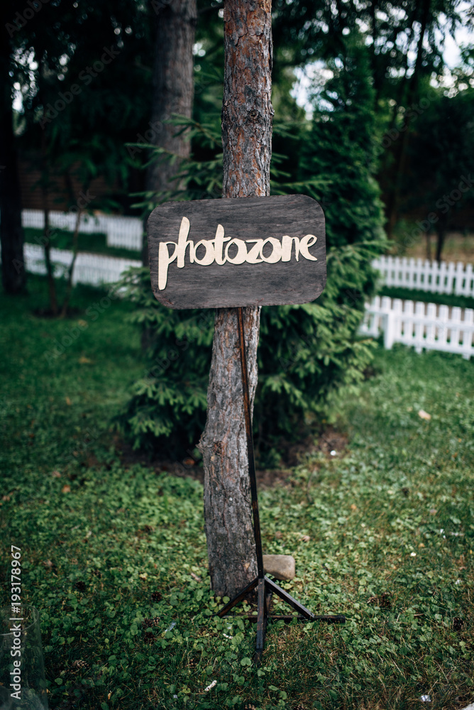Wooden plaque with inscription photozone on the pine
