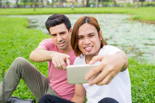Playful Men Taking Selfie on Smartphone in Park © Mangostar