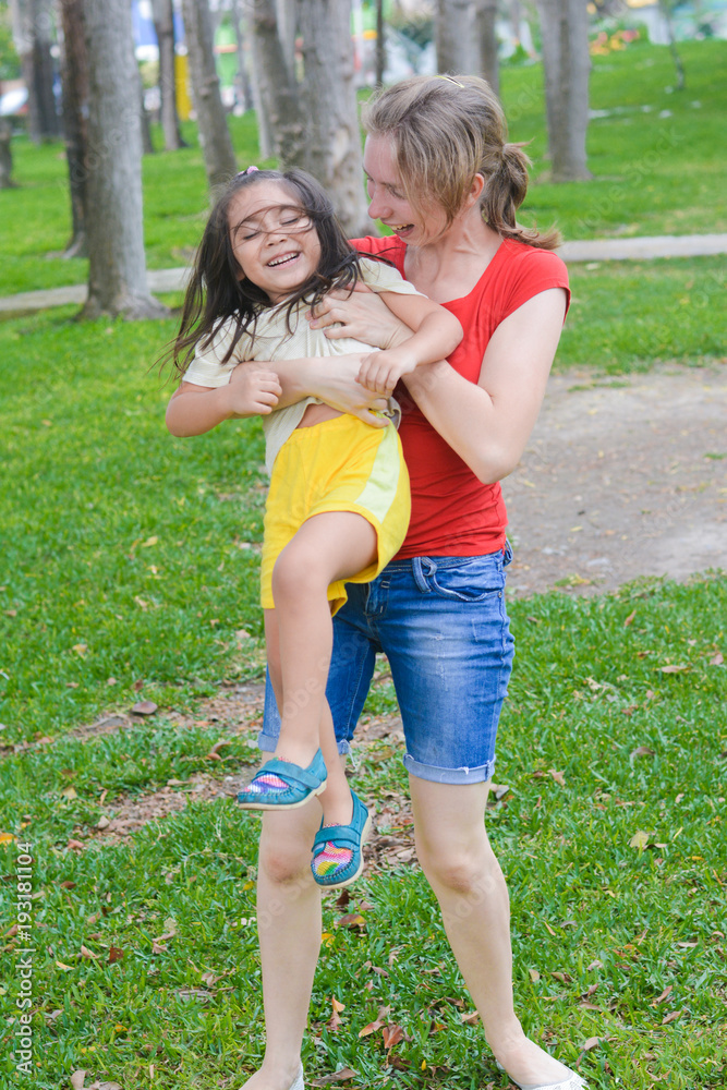 Happy biracial family in the summer park - caucasian mom with her little latin daughter having fun. Happy biracial family in the summer park - caucasian mom with her little latin daughter having fun.