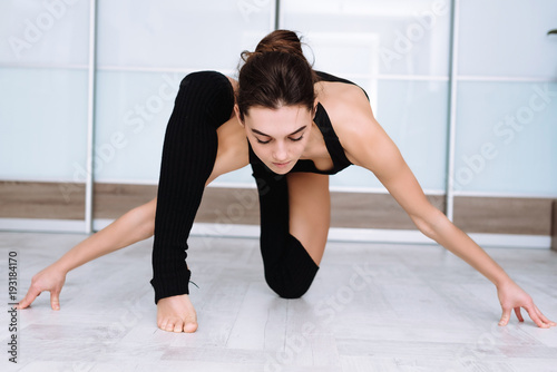 sports model girl doing asanas. beautiful brunette practicing yoga in the interior