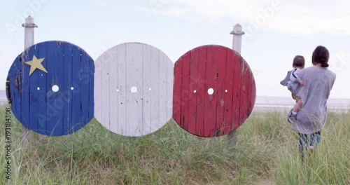 Mother and son walk past acadian flag artwork going towards beach