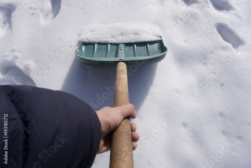 Man with a snow shovel. Man shovelling snow from pathway photo