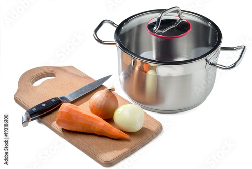 Stainless cooking pot with vegetables and knife on a cutting board isolated on white.