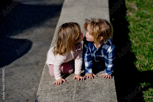 Boy and girl kiss on stone kerb on sunny day © Volodymyr