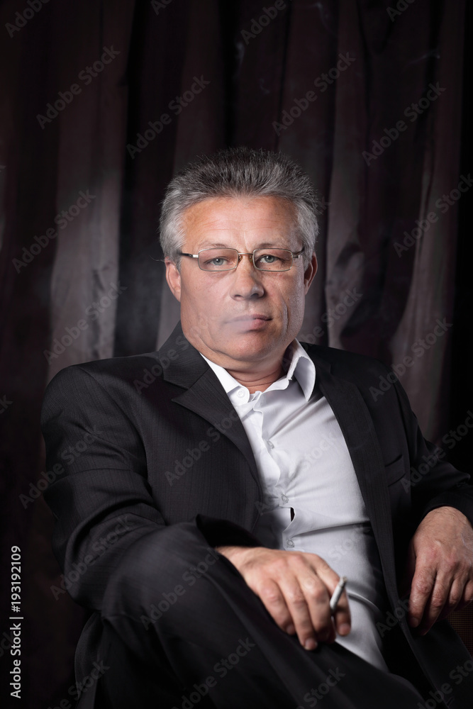 senior businessman with a cigarette,sitting in a chair
