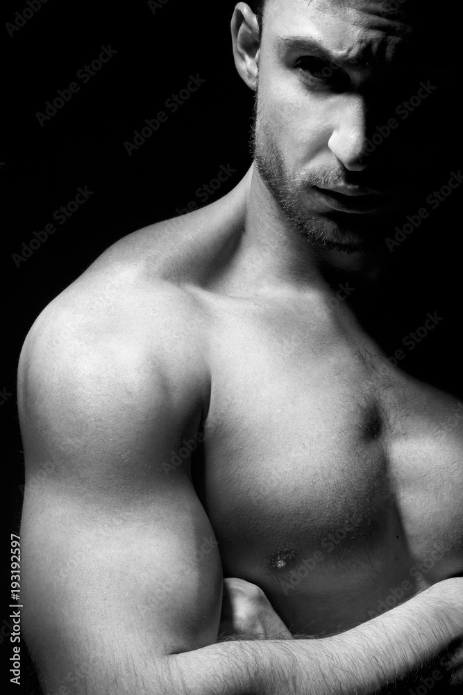 Big and strong muscular man in posing in a low light. Fitness model or a trainer showing his biceps, shoulders and chest. Angry mma fighter or a Bodybuilder is ready to kick ass. Big and strong muscular man in posing in a low light. Fitness model or a trainer showing his biceps, shoulders and chest. Angry mma fighter or a Bodybuilder is ready to kick ass.