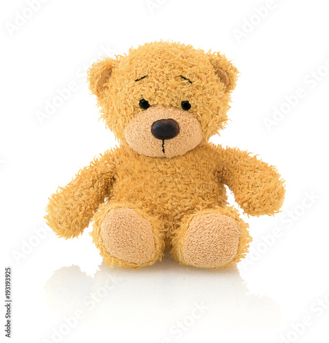 Cute bear doll isolated on white background with shadow reflection. Playful bright brown bear sitting on white underlay.