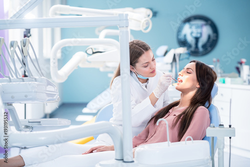 people, medicine, stomatology and health care concept - happy female dentist with mirror checking patient girl teeth up at dental clinic office photo