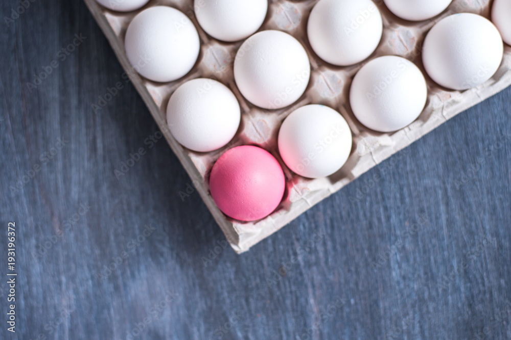 One pink egg and a cardboard box with eggs One pink egg and a cardboard box with eggs