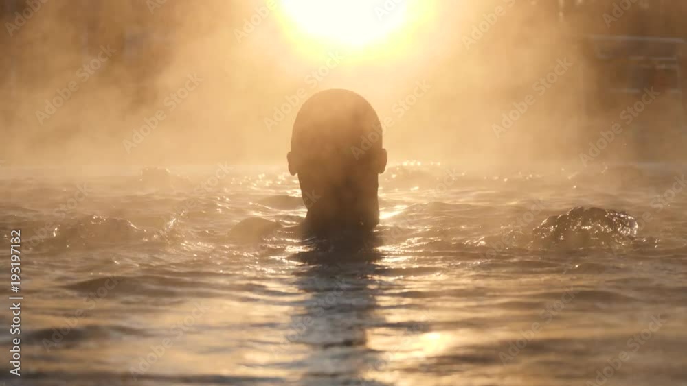Geothermal spa. Woman relaxing in hot spring pool outdoors. Girl enjoying bathing in a blue water lagoon tourist attraction at sunset. Slow motion