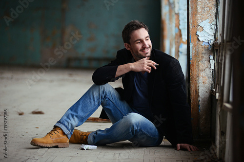 Mysterious handsome man with sneaky look. man with beard smiling. sexy guy in a dark jacket with confident face. Sexy and smart man with beautiful eyes. businessman on a dark romantic background.