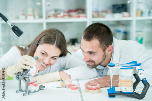 Young team of dental technicians making teeth prostetics. Process of making denture.