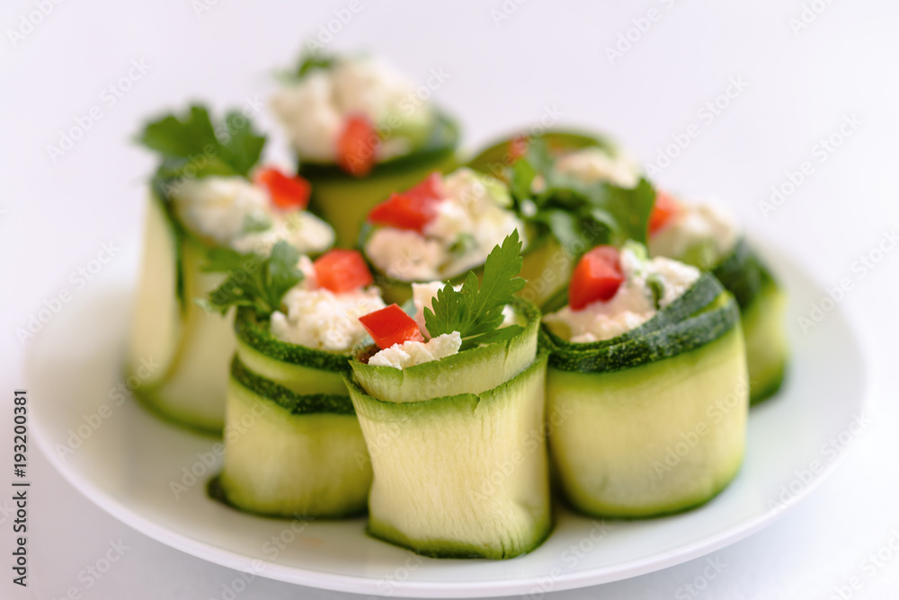 Rolls of zucchini stuffed with cheese and chives and red paprika.