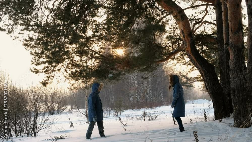 Man and woman playing snowballs in the winter forest. Sunset in the winter forest. Man and woman playing snowballs in the winter forest. Sunset in the winter forest.