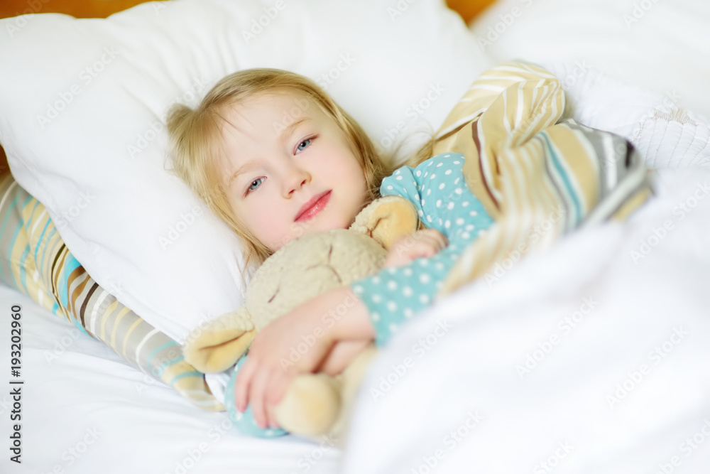 Adorable little girl sleeping in the bed with her toy. Tired child taking a nap under white blanket. Adorable little girl sleeping in the bed with her toy. Tired child taking a nap under white blanket.